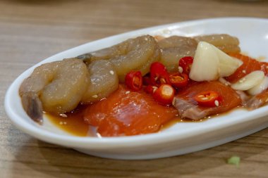 Acı biber ve sarımsakla kaplı taze çiğ karides ve somonla kaplı baharatlı deniz ürünleri tabağı..