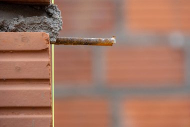 İnşaat alanının yakın çekimi tuğla bir duvarın köşesini gösteriyor. Demiri açık ve taze havan topu var. Odak noktamız inşaat süreci..