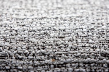 Açık gri ve koyu renkli ipliklerin karışımı sıkıca dokunmuş bir kumaşın yakın çekim görüntüsü ince desenli bir desen oluşturur..