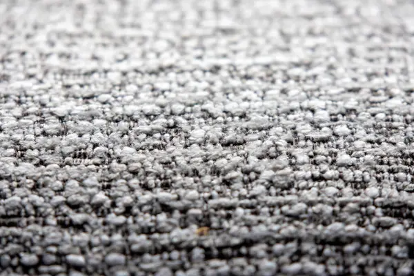 Açık gri ve koyu renkli ipliklerin karışımı sıkıca dokunmuş bir kumaşın yakın çekim görüntüsü ince desenli bir desen oluşturur..