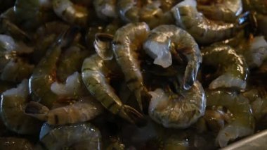 Çok sayıda soyulmuş kaplan karidesi bir restoranın vitrininde buzun üzerinde yatıyor.