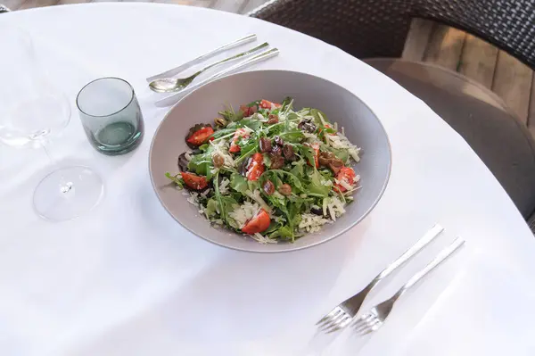 stock image A fresh vegetable salad with cheese served on a white tablecloth, set for an elegant outdoor meal.