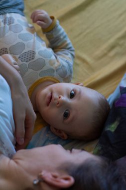 Küçük bebek meraklı surat, annesiyle yatakta yatıyor.