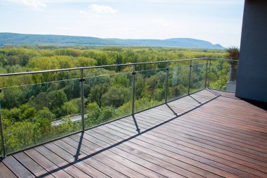 Apartment balcony scenery view with exotic grooved cumaru wood decking and modern glass railing clipart