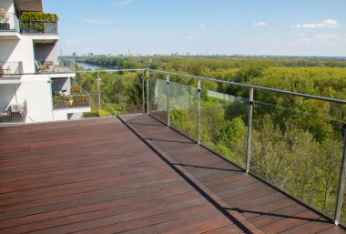 Egzotik ahşap döşemeli balkon manzaralı ve cam parmaklıklı modern mimari dairesi.