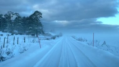 Huzurlu ve huzurlu bir kar yolu zarif bir şekilde genişliyor, dramatik bulutlar, cennet gibi bir kış manzarası sergiliyor.