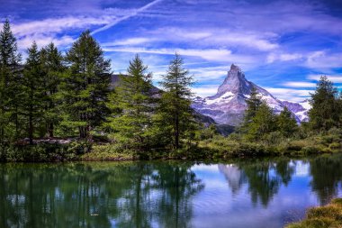 Matterhorn peak (4478 m) and his reflection on the Grindjisee lake during a summer day. Photo taken around Zermatt, Switzerland on 17th of August 2019. clipart