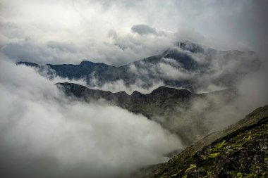 Dağ sırtı silueti kalın ve yoğun bir sis tabakasının içinde görüldü. Fotoğraf 12 Temmuz 2020 'de Romanya' daki Karpatlar 'ın Retezat Dağları' nda yapılan bir yürüyüş sırasında çekildi.