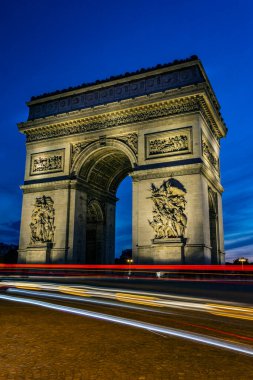 Çarpıcı bir günbatımında trafik ışığı izleri taşıyan Zafer Kemeri. Fotoğraf 22 Nisan 2022 'de Paris, Fransa' da çekildi..
