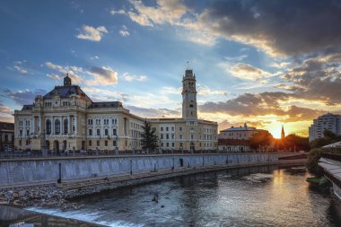 Oradea belediye binası ve Crisul Repede nehri alacakaranlıkta. Fotoğraf 16 Temmuz 2022 'de Romanya' nın Bihor ilinin Oradea kentinde çekildi..