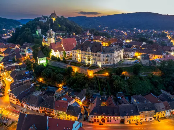 Ortaçağ kalesinin havası ve alacakaranlıkta Sighisoara şehri. Fotoğraf 14 Ağustos 2023 'te Romanya' nın Transilvanya bölgesindeki Sighisoara kentinde çekildi..