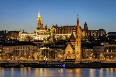 Matthias Church tower with the Fisherman Bastion and he Szilgyi Dezs reformed Church illuminated at the blue hour. Photo taken on 24th January 2025 in Budapest, Hungary. clipart