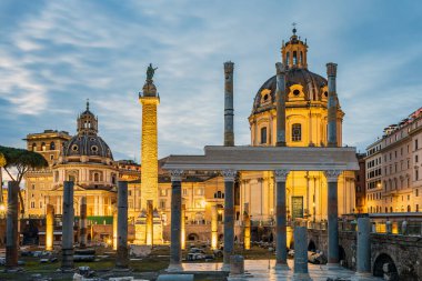İmparator Trajan 'ın oturum ve sütununda akşam vakti. Arka planda Loreto 'lu Santa Maria' nın aydınlatılmış kilisesi duruyor. Fotoğraf 12 Şubat 2025 'te İtalya' nın Lazio bölgesinde çekildi..
