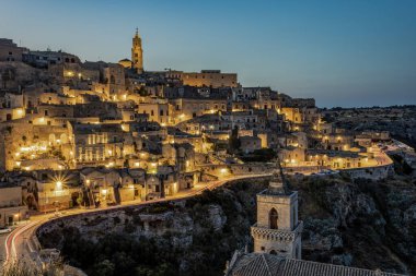 Mavi saat Matera 'nın eski şehrini aydınlattı, aynı zamanda Mağara Şehri olarak da bilinir. Fotoğraf 26 Haziran 2025 'te çekildi, Matera ili, Basilicata bölgesi, Güney İtalya.