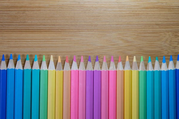 木製のテーブルの背景に鉛筆のヒントで作られた行の厳しいラインで敷設色鉛筆のグループを閉じる 色鉛筆 コピースペース パステルカラーの概念 背景概念 教育の概念 — ストック写真