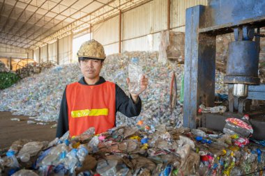 Geri dönüşüm, geri dönüşüm ve yeniden kullanım endüstrisinde geri dönüşümlü plastik bir su şişesi tutan Asyalı mühendis..