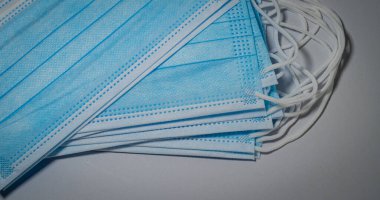 Mavi tıbbi maskeler yakın çekim için gri arka planda katmanlar halinde dizilmiş, bakteri koruma konsepti.