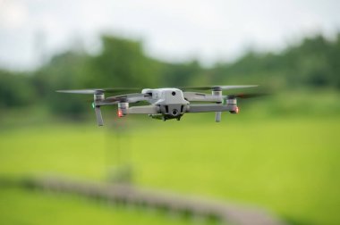 Açık havada uçan bir dron, pirinç tarlasında drone, arka planda yeşil pirinç tarlaları, tarım endüstrisinde teknolojik yenilik.