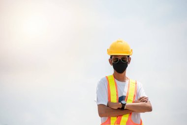 Asyalı mühendis ayakta dururken kameraya bakarken çelik yelek giyiyor. Uzayı kopyala.