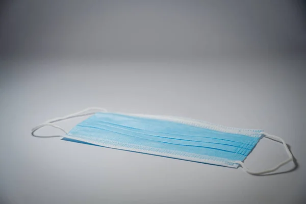 Blaue Chirurgenmaske Mit Gummi Ohrenbändern Auf Mittelgrauem Hintergrund Bakterienschutzkonzept — Stockfoto