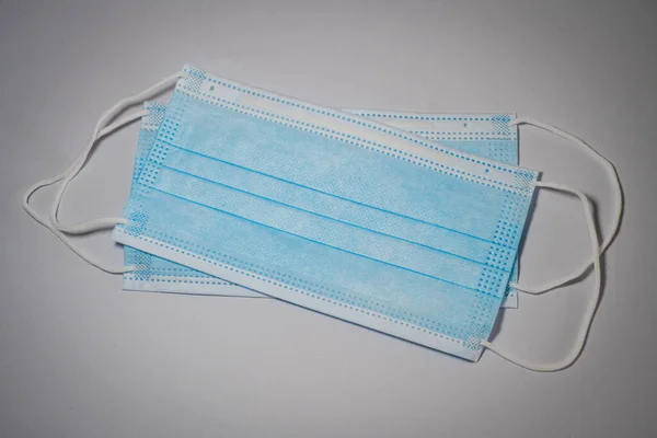 Two blue surgical mask with rubber ears straps set in middle on gray background, Bacteria protection concept.