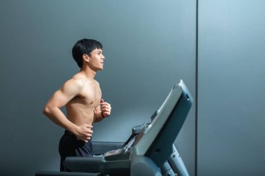 Asyalı yakışıklı adam fitness merkezinde koşu bandında koşan formda bir kas..