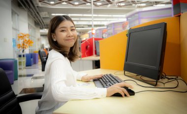 Güzel Asyalı ofis kadını işte mutlu ve şirket ofisinde gülümsüyor..