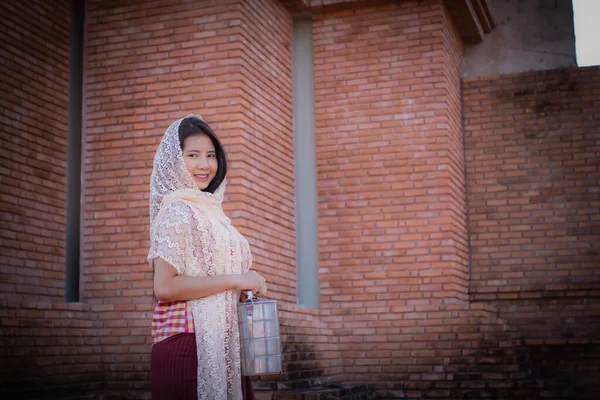 stock image Beautiful thai girl in traditional thai dress covered with a white cloth standing and looking to to the camera in an old temple with a smile.