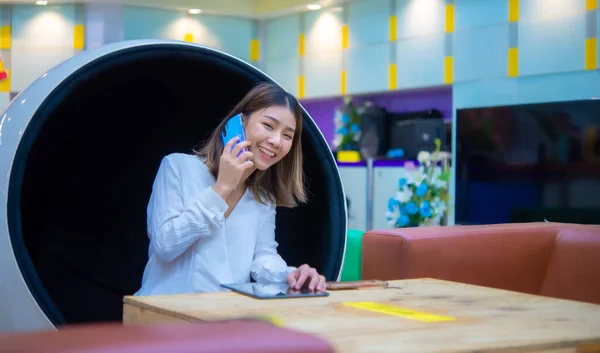 美丽的亚洲女商人坐在现代的圆椅子上 用电话与顾客微笑交流 数字营销 — 图库照片
