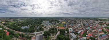 Şehrin panoramik manzarası, yeşil ağaçlar ve mavi gökyüzü doğanın ve kentsel gelişimin eşsiz bir karışımıdır..
