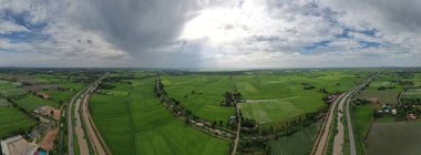 Pirinç tarlalarının, yeşil ağaçların ve dağların panoramik görüntüsü, duyuları büyüleyen çarpıcı bir doğal manzaradır..