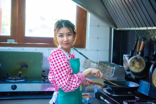 아름다운 아시아인 부엌에서 툴라와 프라이팬 요리를 얼굴에 미소를 머금고 카메라를 — 스톡 사진