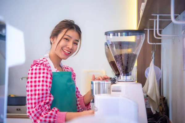 beautiful asian barista staff use coffee maker while looking at the camera with a smile, Business and finance.