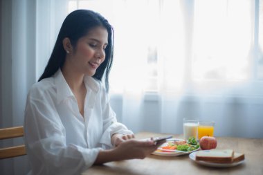 Davranışlarından açıkça anlaşılıyordu ki, bu, kahvaltı için saf neşe ve mutluluk anıydı. Güzel Asyalı kız telefonuyla oynaşırken....