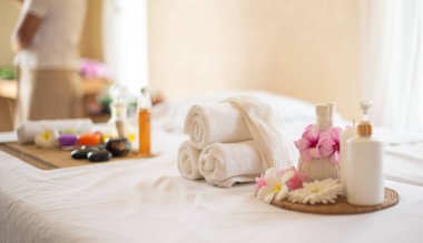 Mumlu spa kompozisyonu, tuzlu frangipani çiçeği kasesi ve ahşap masadaki bitkisel top rahatlatıcı ve canlandırıcı bir spa deneyimi için çok güzel ve davetkar bir ortam..