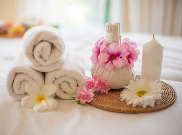 The white linens and scented candle on the bed create a peaceful and relaxing spa atmosphere.
