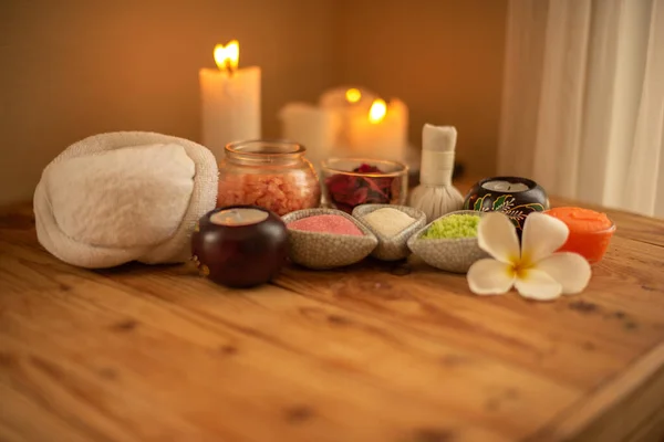 Mumları olan güzel bir spa kompozisyonu. Frangipani çiçek kasesi, ahşap masada tuz ve bitkisel top..