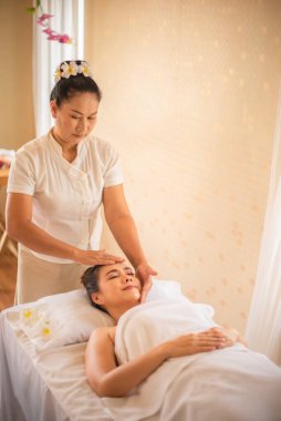 Asyalı güzel bir kadının dikey resmi profesyonel bir masözün kafasına zevkle masaj yapmasına izin verdi..