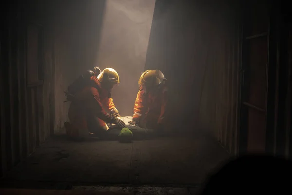 2人の消防士が部屋のダミーモデルのパルスをチェックすることで犠牲者の状況を処理する練習をしています — ストック写真