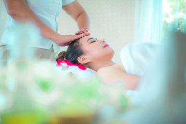 Profesyonel bir masözün yan görünüşü, gül yapraklarıyla süslenmiş bir yatağın üzerine bitki masajı yapmaktır..