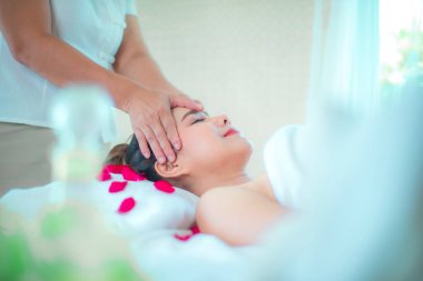 Yatağa gül yaprakları serpiştirilmiş kadın müşteriye profesyonel masöz kafa masajı..