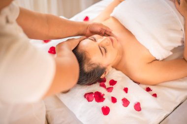 Güzeller güzeli Asyalı müşterimiz spa odasına gül yaprakları serpiştirilmiş olarak uzanmış vücudunu ve zihnini mükemmel bir uyum içinde yenilenmiş ve ferahlamış hissediyor..