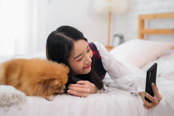 美丽的亚洲女人挣扎着让她的狗安静地等待着拍照 但却禁不住笑着看着它的能量 — 图库照片