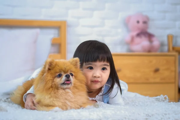 一个小女孩和一只狗躺在卧室的床上之间很可爱 — 图库照片