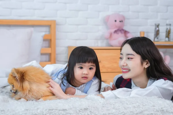 The scene was one of pure innocence and beauty as the girls and the dog enjoyed each other\'s company on the comfortable bed in the peaceful bedroom.