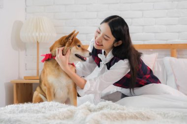 Güzel Asyalı kadının neşeli ifadesi sevgili evcil hayvanıyla vakit geçirmekten duyduğu neşeyi gösteriyordu. Şirin köpeğin rahat tavrı da güçlü bağlarının bir kanıtıydı..