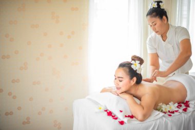 Kaplıca odasındaki yatağın etrafına serpilmiş gül yapraklarının hoş kokusu havayı doldurdu ve Asyalı güzel kadının masaj seansı için rahatlatıcı bir atmosfer yarattı..