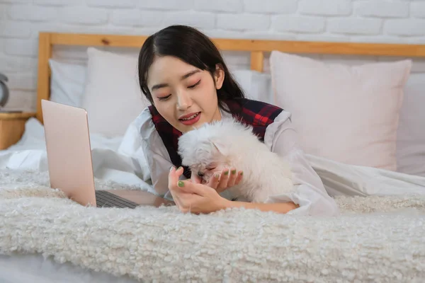 The warm and cozy atmosphere of the bedroom along with the woman's playful energy and the cute dog's endearing nature made it a beautiful moment that was worth cherishing.
