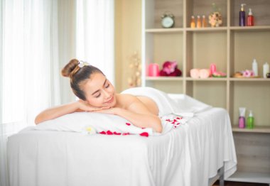 Gözleri kapalıyken ve yüzleri yumuşamışken güzel Asyalı kadın, spa odasında güllerle saçılmış bir yatakta huzur dolu bir anın tadını çıkarıyor gibi görünüyordu..