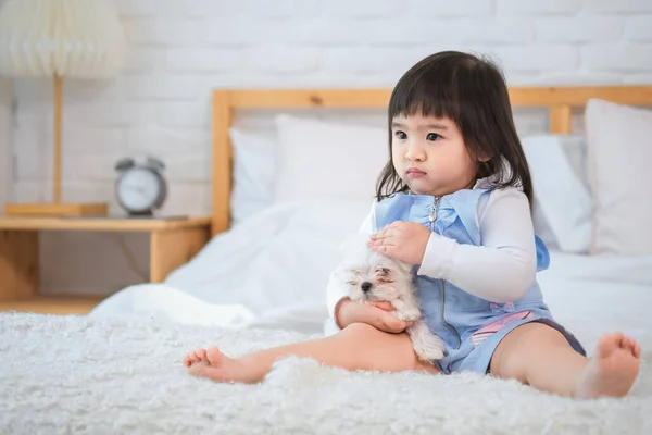 The peaceful scene on the bed was filled with love and affection with the little girl holding her furry friend enjoying each other\'s company on bed in bedroom.